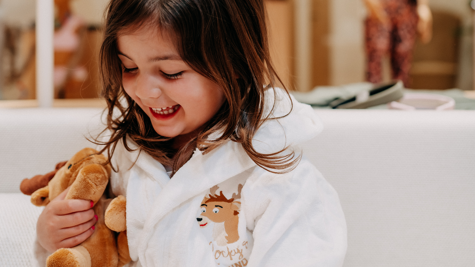 Girl in bathrobe holding Rocky the deer plush toy at Forsthofgut.