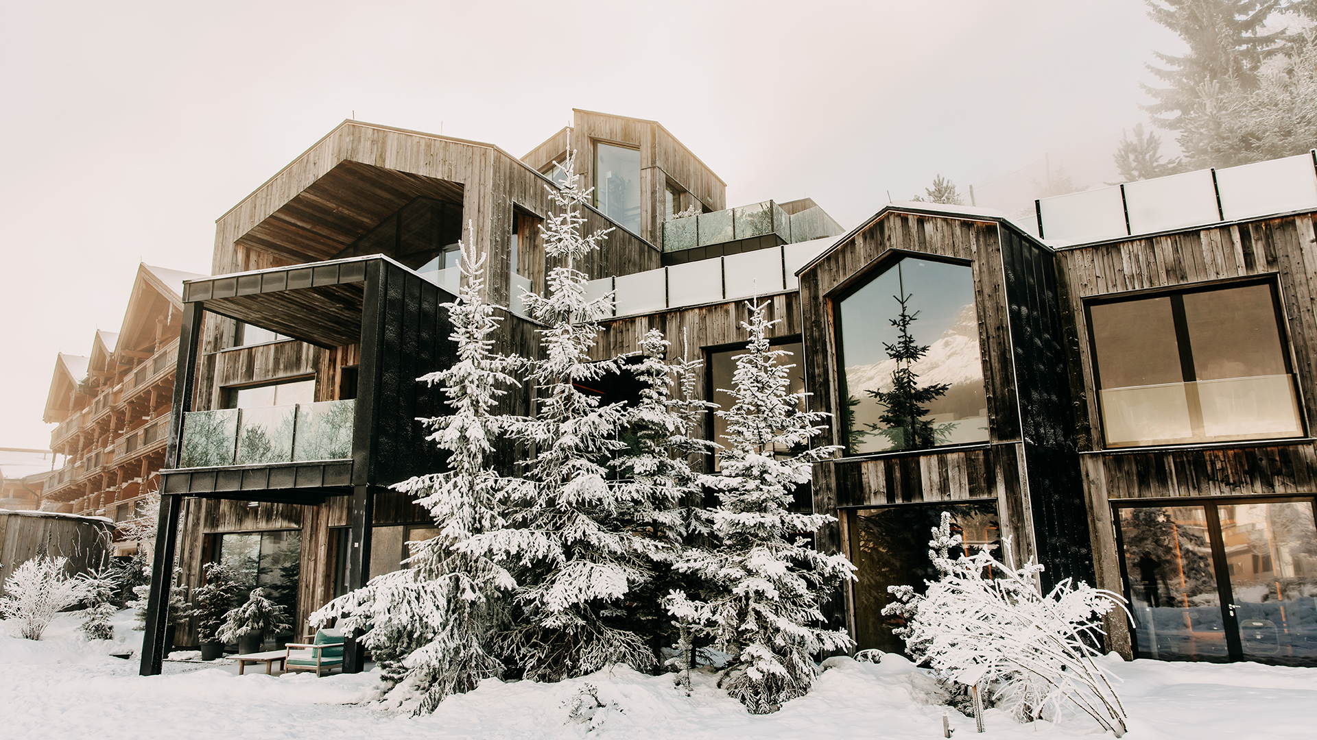Das Forsthofgut im Winter mit verschneiten Tannen vor dem Haus.
