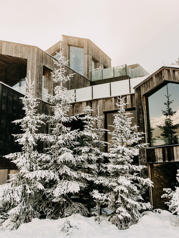 Das Forsthofgut im Winter mit verschneiten Tannen vor dem Haus.