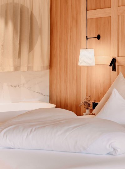A cozy bed is visible in the room, with an elegantly positioned freestanding bathtub directly behind it