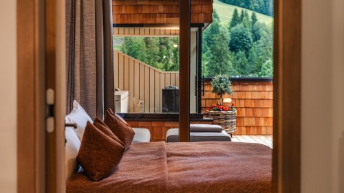 Bedroom with a view of the terrace, featuring a neatly made bed covered with a reddish bedspread and decorative pillows.