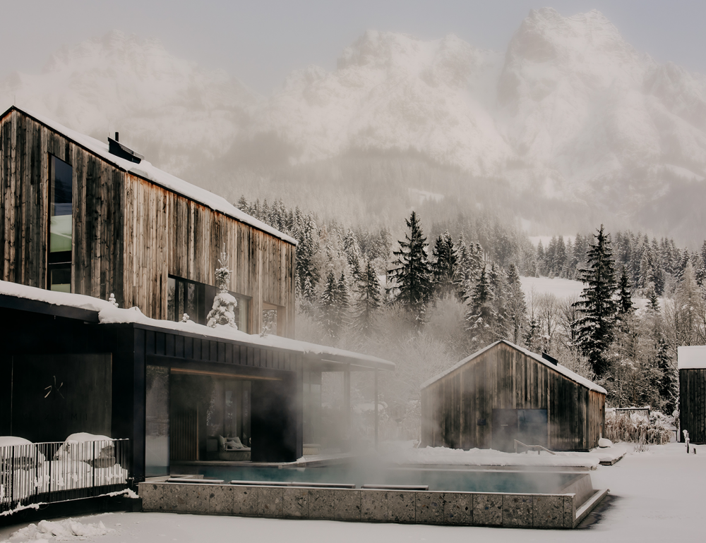 Außenaufnahme des beheizten Seepools im Forsthofgut, umgeben von verschneiter Winterlandschaft.