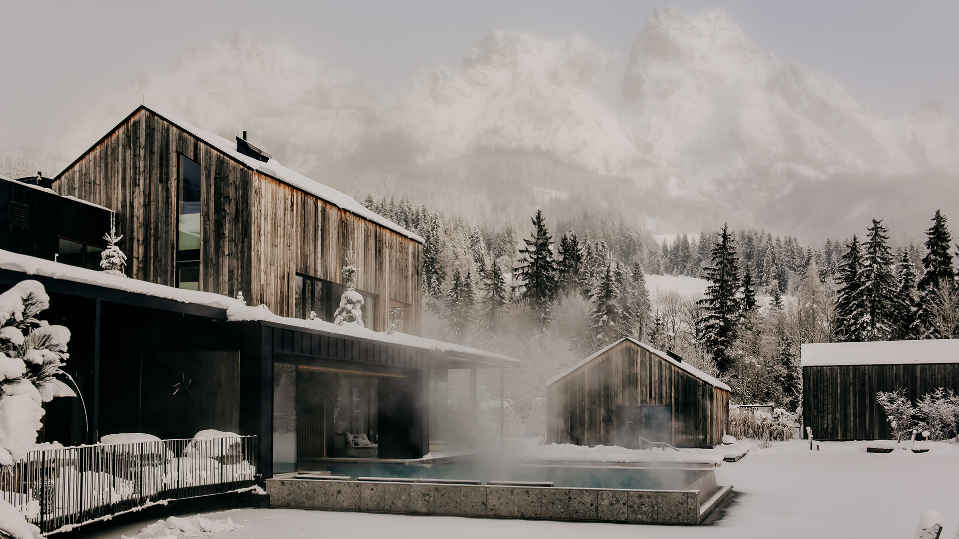 Außenaufnahme des beheizten Seepools im Forsthofgut, umgeben von verschneiter Winterlandschaft.