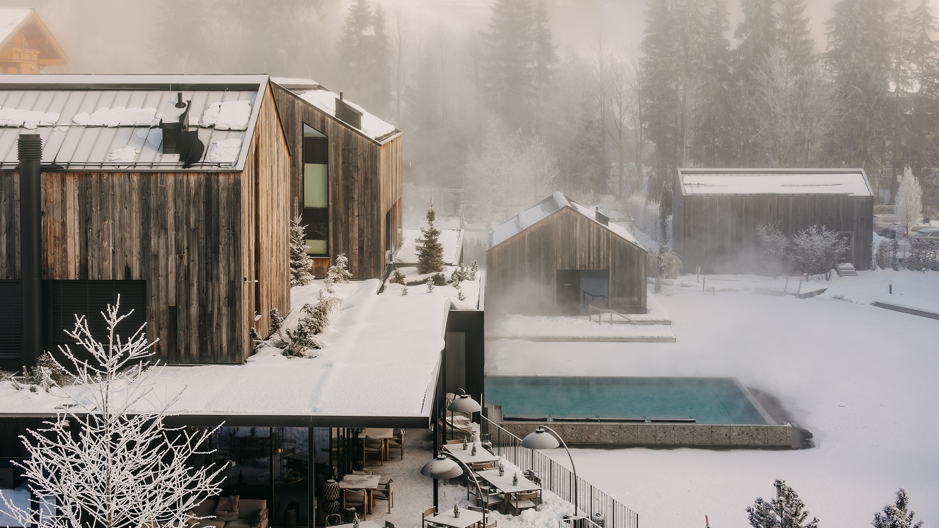 Exterior view of the waldSPA at Naturhotel Forsthofgut with heated pool and snowy winter scenery.