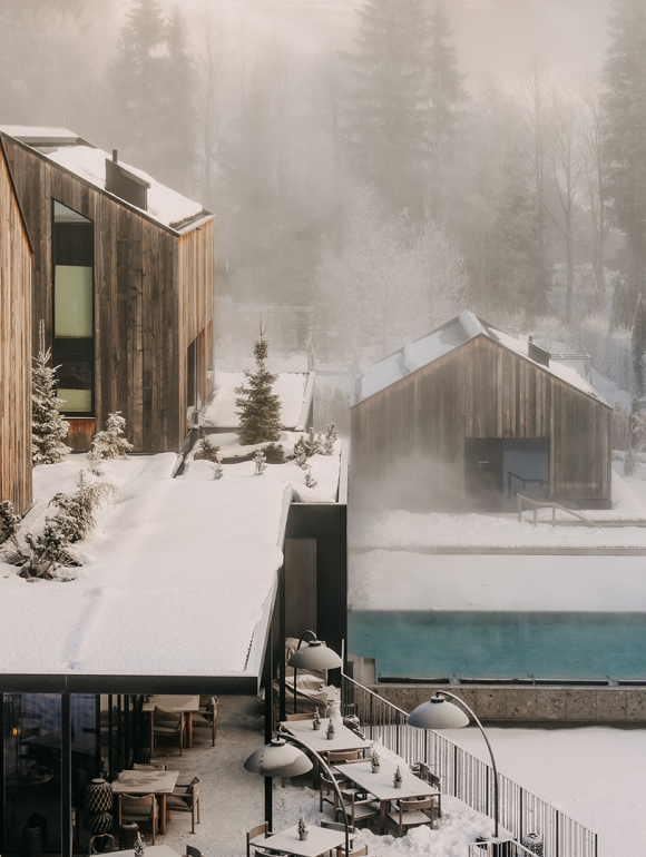 Exterior view of the waldSPA at Naturhotel Forsthofgut with heated pool and snowy winter scenery.