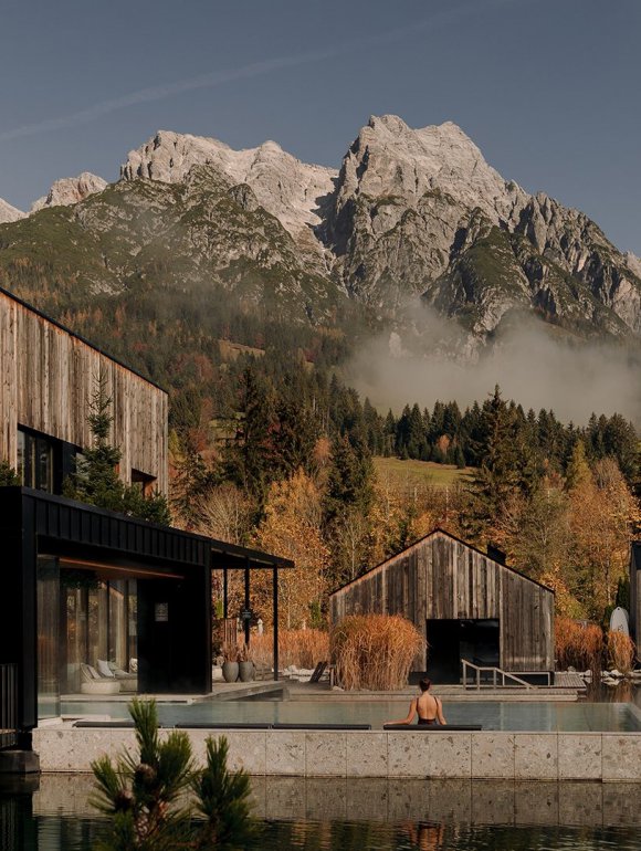 Blick auf die Seesauna und den beheizten Außenpool „Seepool“ im Forsthofgut, umgeben von bunten Herbstbäumen und Bergpanorama.