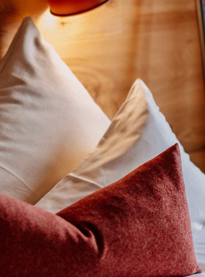 Close-up of a cozy bed with red decorative cushions and white bedding.