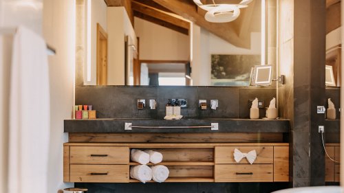 Modernes Badezimmer mit eleganter Armatur und einem großen Spiegel, der von integrierter LED-Beleuchtung erhellt wird.