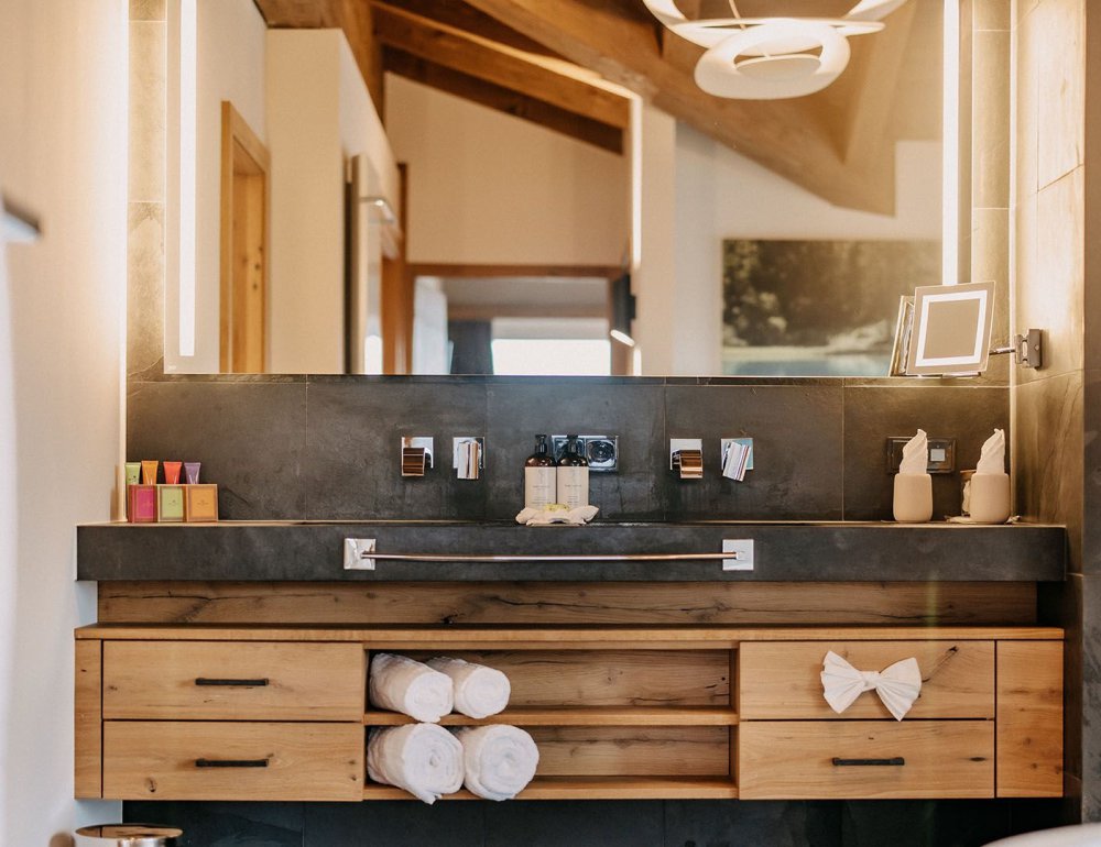 Modern bathroom featuring a sleek faucet and a large mirror softly illuminated by integrated LED lighting.